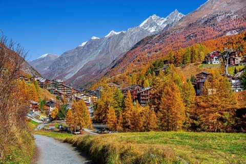 Autumn landscape with hiking trail and view of the village and dome 4545m of the Mischabel group,