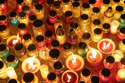 Colorful candle jars glowing warmly in the night. A huge number of multicolored burning candles and