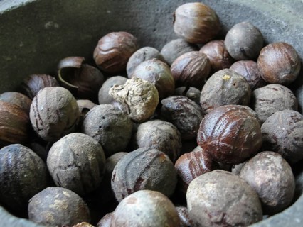 Whole nutmeg in a stone mortar at the market, texture, background, A collection of whole nutmegs in