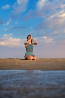 Beach scene featuring yoga, a young woman, vajrasana, thunderbolt pose, a woman, and kneeling