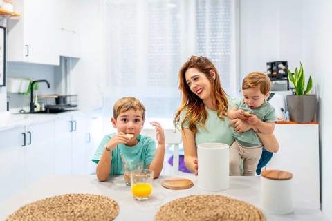 Happy family of three having breakfast sitting on the kitchen at home before school