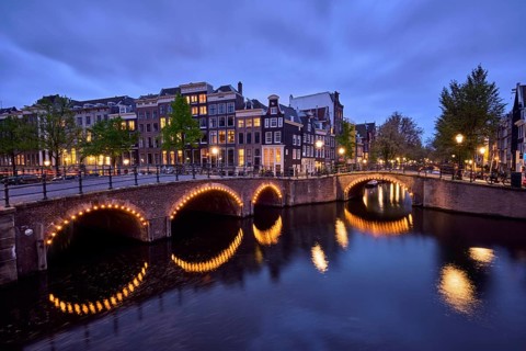 Night view of Amterdam cityscape with canal, bridge and medieval houses in the evening twilight