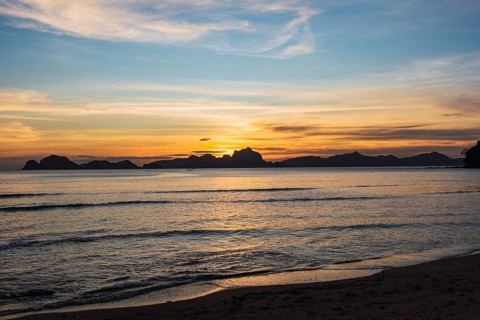 A breathtaking sunset over a serene sea in the Philippines, highlighting the silhouette of islands