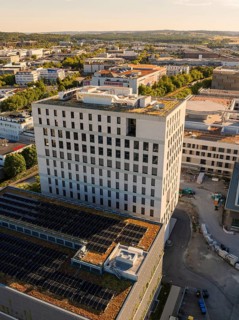 High-rise building with solar panels in an industrial area surrounded by other buildings and roads,