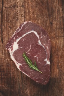 Raw steak, beef steak, rib eye steak, on a cutting board, freshly frozen, with spices and herbs, on