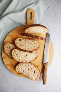 Top view of fresh homemade sourdough bread slices neatly placed on a wooden cutting board next to a
