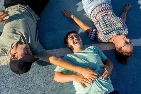 A Down syndrome teenager enjoys a sunny day lying on a sports court with family Emphasizing the joy