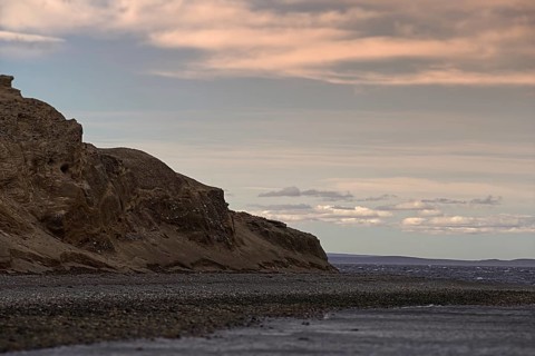 The rock of the island Isla Magdalena, the penguin colony in front of a cloudy sky, Punta Arenas,
