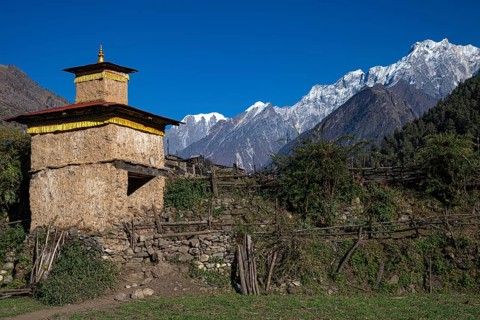 Small Buddhist Torstupa in front of snow-capped mountains of the Siringi Himal mountain range, Tsum