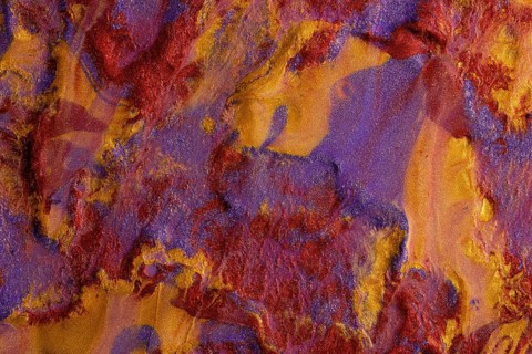 An artistic background showcasing a vibrant blend of red, purple, and gold metallic paints,