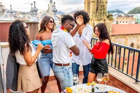 Multiracial friends dancing happily during tropical party in a rooftop with city views during
