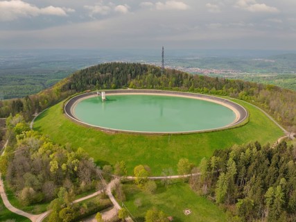 Upper reservoir, aerial view shows large round reservoir surrounded by forest and landscape, Glems