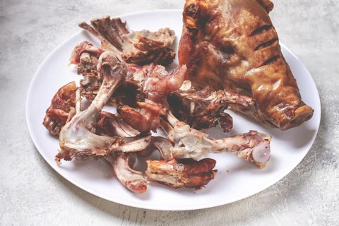 Roast pork head, with remnants of bones and meat, on a white platter, no people, close-up