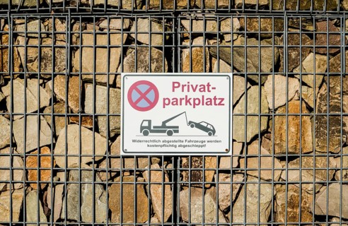 Sign on a gabion filled with stones, German for private car parking, Germany