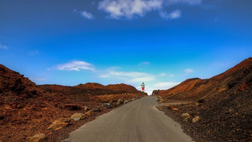 Punta de Teno, Lonely road leads to a lighthouse through red rocks under blue sky, Masca, Barranco