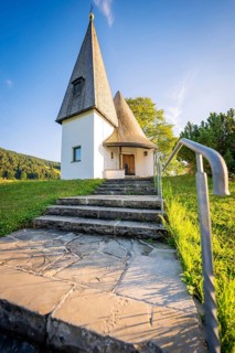 Stone staircase leads to the white-painted chapel on a green meadow in sunny weather, Bruder Klaus