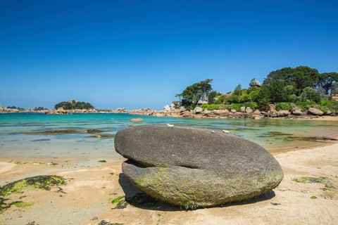 Beach with rocks and sand at the Plage Saint Guirec, with clear blue sky and colors as in the
