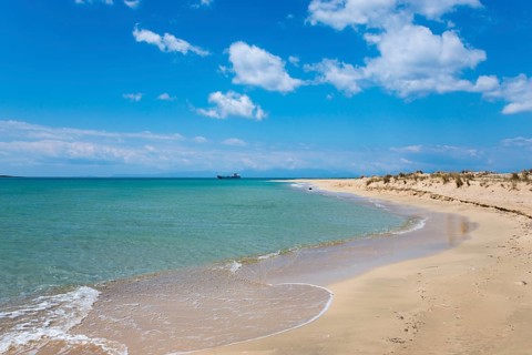 An unspoilt sandy beach with turquoise sea and sand dunes under a cloudy sky, Pounta beach near