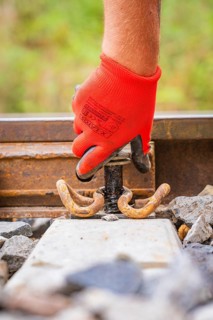 Close-up of a red-gloved hand holding a tool on rails, track construction, Hermann Hessebahn, Calw,