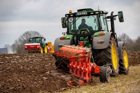 Tractor with a plough preparing the soil of a field for planting, Agriculture, Spring
