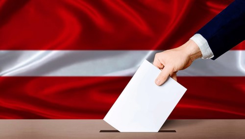 Hand placing a ballot in ballot box with the Latvian flag in the background. Latvia Parliamentary