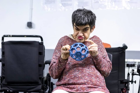 Woman in a mental health residence engages in a therapeutic exercise with a sensory ball. The