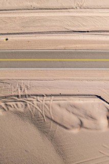 Aerial view of a straight asphalt road cutting through a sandy desert landscape of the argentine