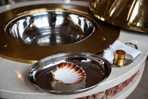 Religious items for a Christian baptism ceremony, including a silver tray with a baptismal shell