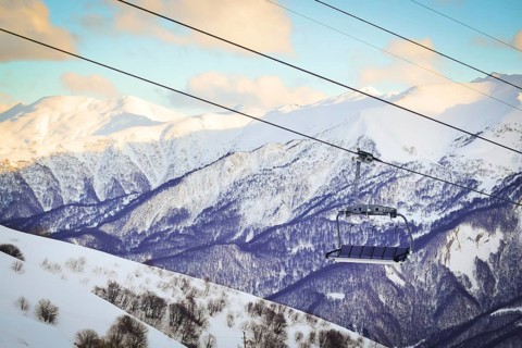 Gudauri six seat blue chair lift with caucasus mountains background. Blank space ski resort closure