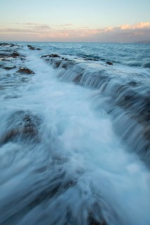 A breathtaking sunset over the coast of Tarifa, Cadiz, showcases the ocean's gentle waves and rocky