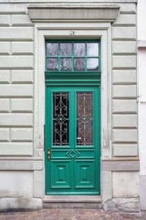 An elegant green door with decorative windows on a classic building in the historic old town of