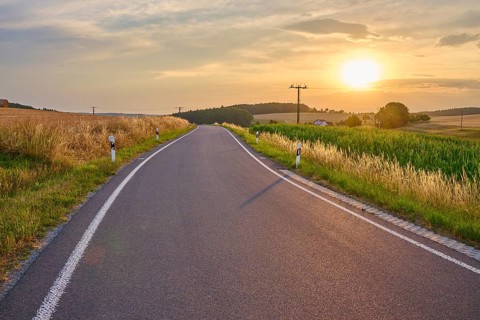 A quiet country road at sunset surrounded by green and golden fields, summer, Reichartshausen,