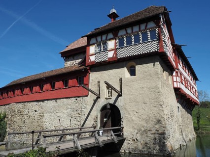 Medieval castle with half-timbering with red accents and wooden elements under a clear sky,