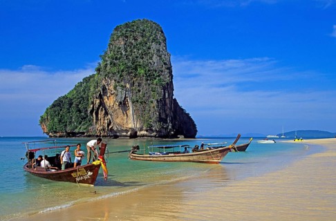 Rocks in the sea, people and longtail boats on Pranang Cave beach, two years in front of the