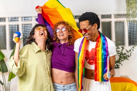 Multi-ethnic young friends celebrating pride party singing karaoke at home