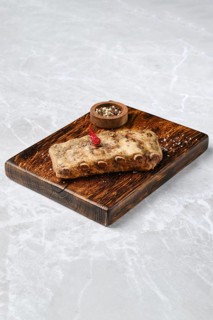 Grilled spicy pork ribs on a rustic wooden board, with a small bowl of mixed spices