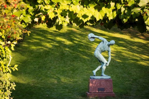 Sculpture of a discus launcher in a green, sunny park area, Botanical Garden or Botanisk Have,