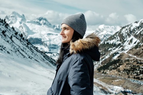 Woman in winter attire enjoying the scenic snowy landscape at Astun Ski Resort, nestled in the