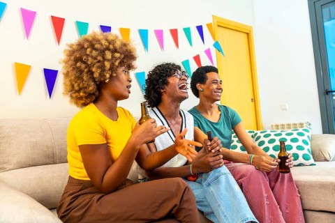 Multi-ethnic friends sitting on the sofa drinking beer during party at home