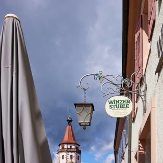 Nose sign of the restaurant and wine bar Winzerstüble, Niggelturm and parasol in rainy weather in