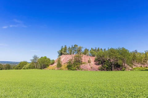 Pile of slag dumps from a Limestone quarry by a lush green field in the countryside, Sweden