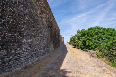 Long castle wall with rocky path, green vegetation next to it, historic, Monsaraz, Évora, Portugal