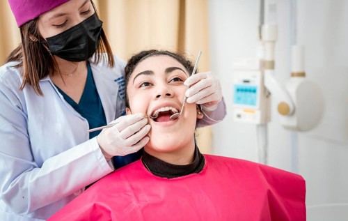 Front view of dentist checking patient with excavator and dental mirror, Dentist checking patient