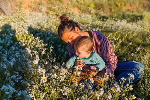 A tender moment between a mother and her young child seated in a blossoming meadow in Samalus,