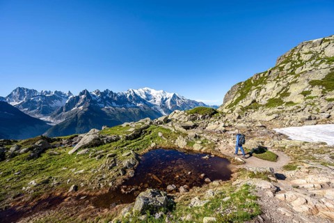 Mountaineer in mountain landscape with small lake, mountain panorama of the Mont Blanc massif with