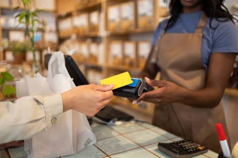 A store clerk in an organic supermarket assists a customer making a purchase with a card payment.