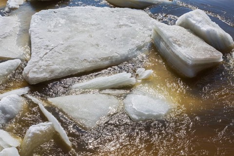 Close-up of large blocks of thick jagged ice floes floating on the surface of the Mille-Iles river