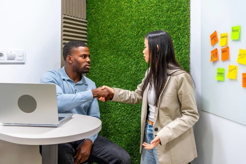 Two businesspeople shaking hands after reaching an agreement in a modern coworking office with a
