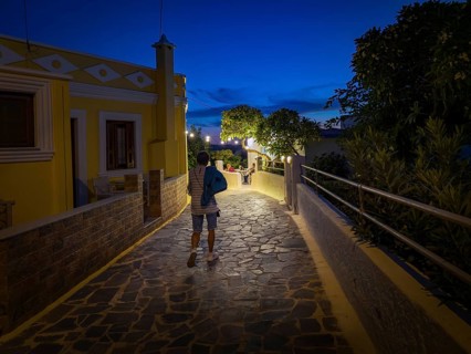 Evening mood of the illuminated promenade of Arkasa, yellow house and strollers in a cosy