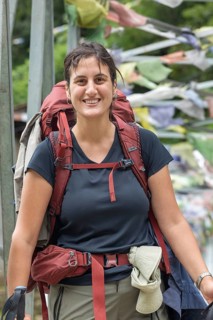 A woman smiles broadly as she embarks on a trek through the Everest region. Dressed in practical